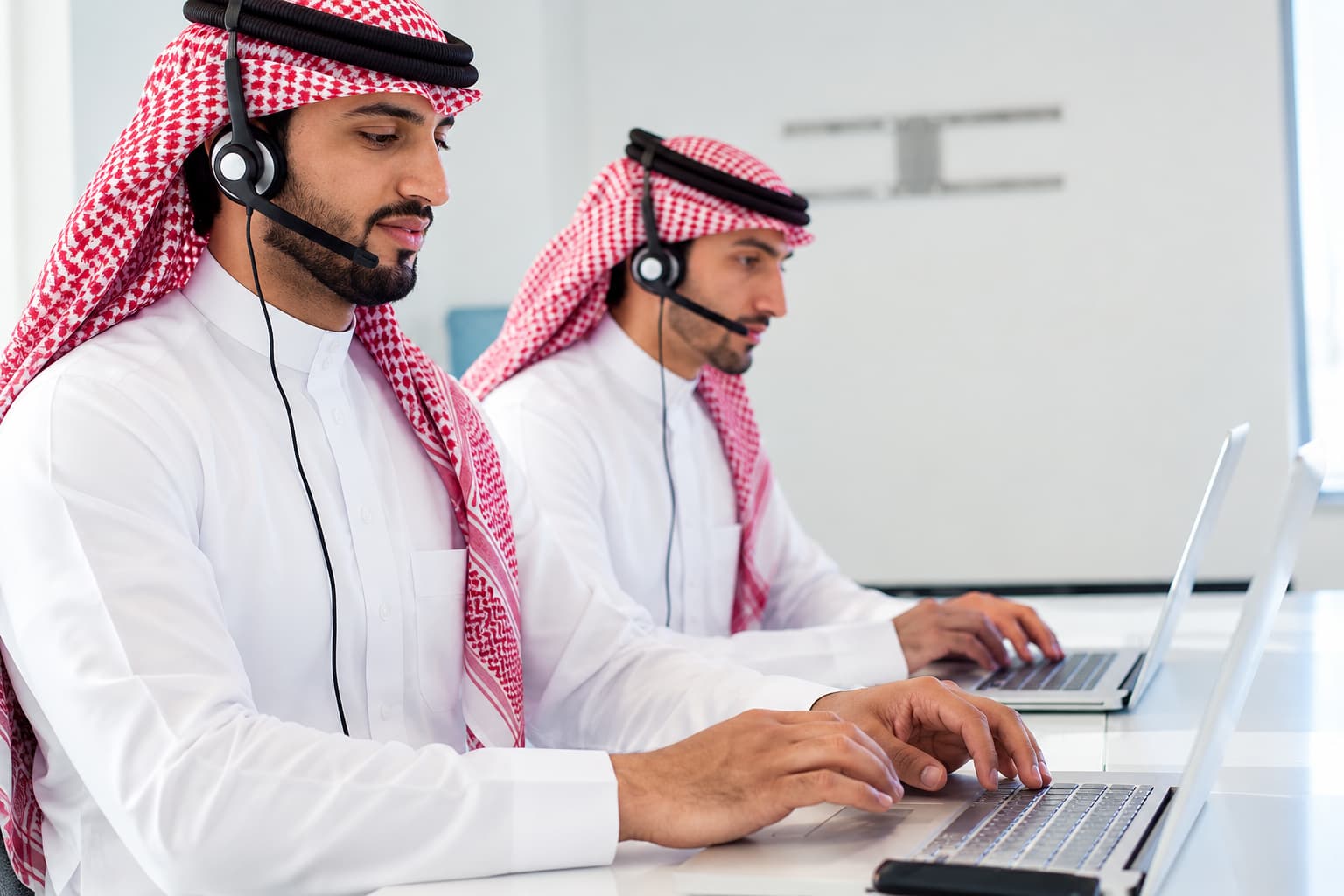 موظفان بسماعات الرأس يعملان على حاسوبيهما